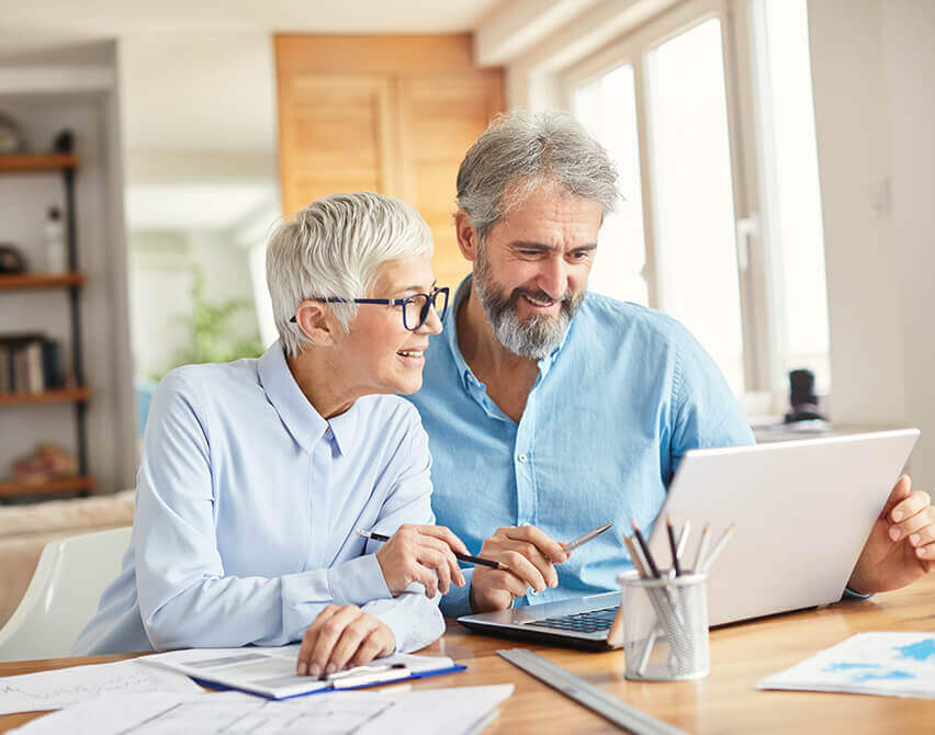 Mature couple at kitchen table with laptop